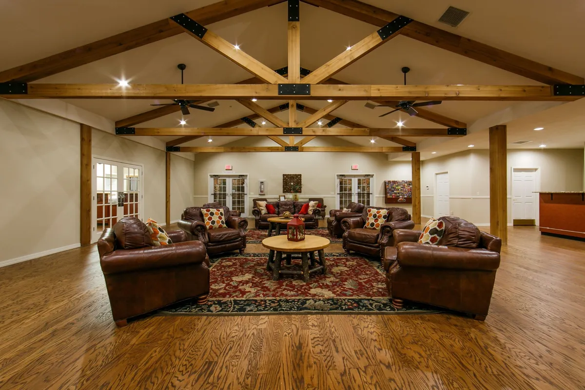 An inviting living area with plush leather sofas set around a wooden coffee table, accented by exposed wooden beams and a decorative rug. The scene exudes comfort and warmth, ideal for socializing and relaxing after dining.